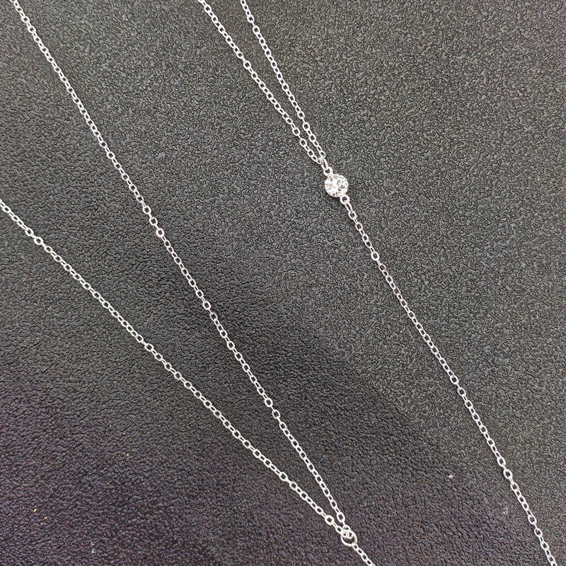 Silver chain necklace on a textured gray background