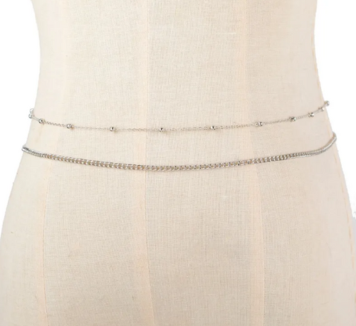 Close-up of a beige dress with a thin silver belt on a mannequin.