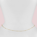 Gold necklace on a person wearing a pink top with a light gray background