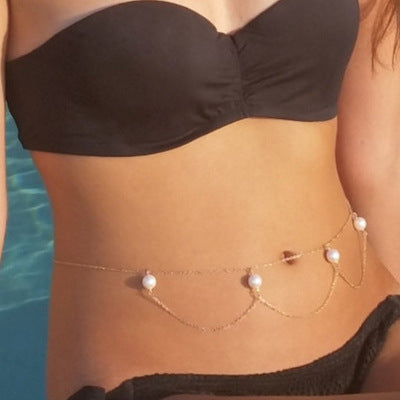 Person wearing a black bikini with pearl waist chain by a pool