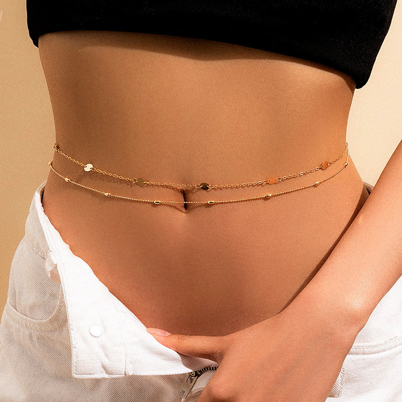 Gold chain belt worn around the waist with a neutral background