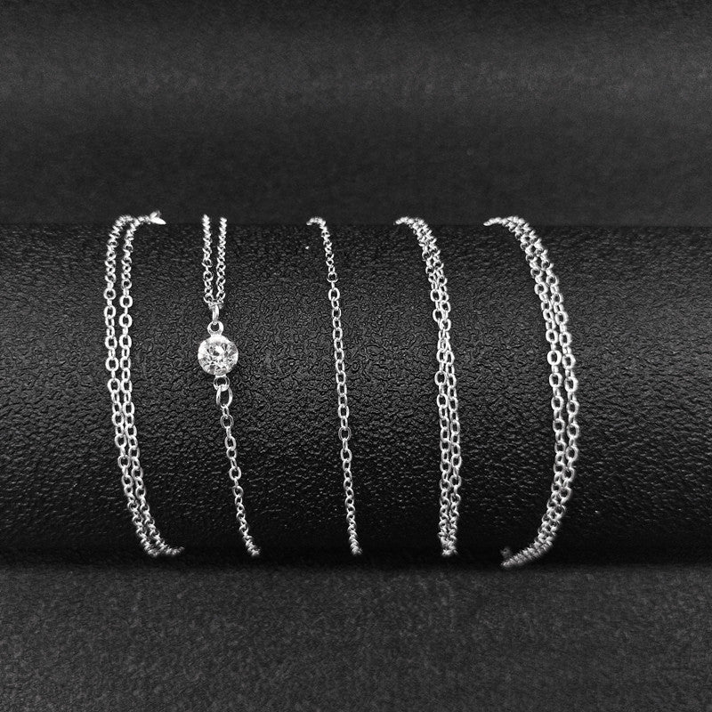 Set of silver chain bracelets on a black textured surface